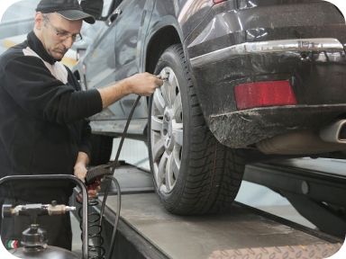 Person pressuring a tire of a lifted car | Madden Auto Repair