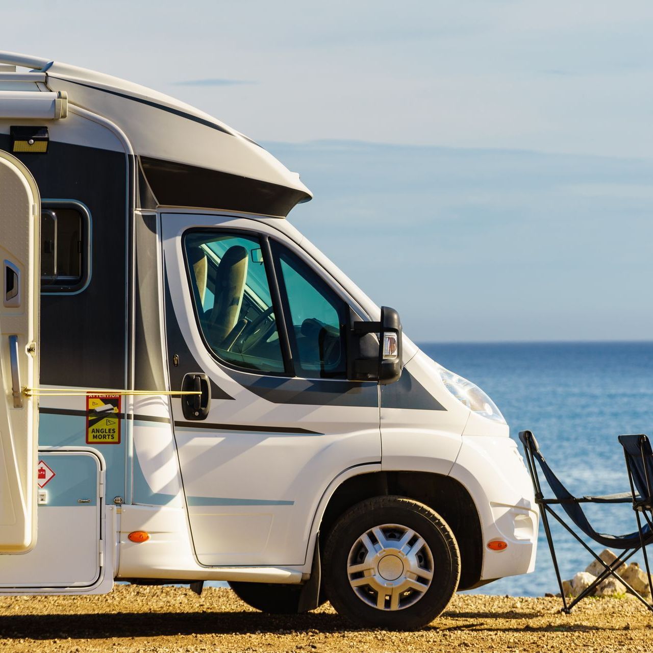 A camper van is parked on the beach near the ocean
