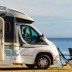 A camper van is parked on the beach near the ocean