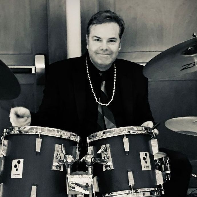 A man in a suit and tie is playing drums