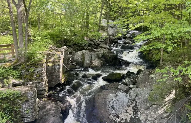 Small waterfall cascading over rocks in a lush green forest, southford falls, ct