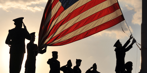 A group of soldiers holding a large american flag