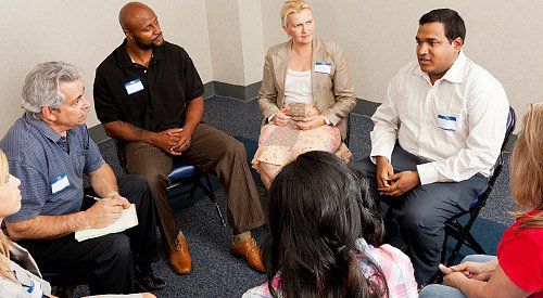 A group of people are sitting in a circle talking to each other.