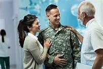 A soldier and his wife are talking to a doctor in a hospital.