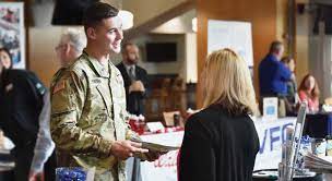 A soldier is talking to a woman at a job fair.