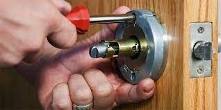 A person is fixing a door lock with a screwdriver.