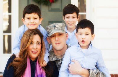 A man in a military uniform is posing for a picture with his family.