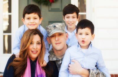 A man in a military uniform is posing for a picture with his family.