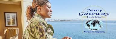 A woman in a military uniform is standing in front of a window overlooking the ocean.