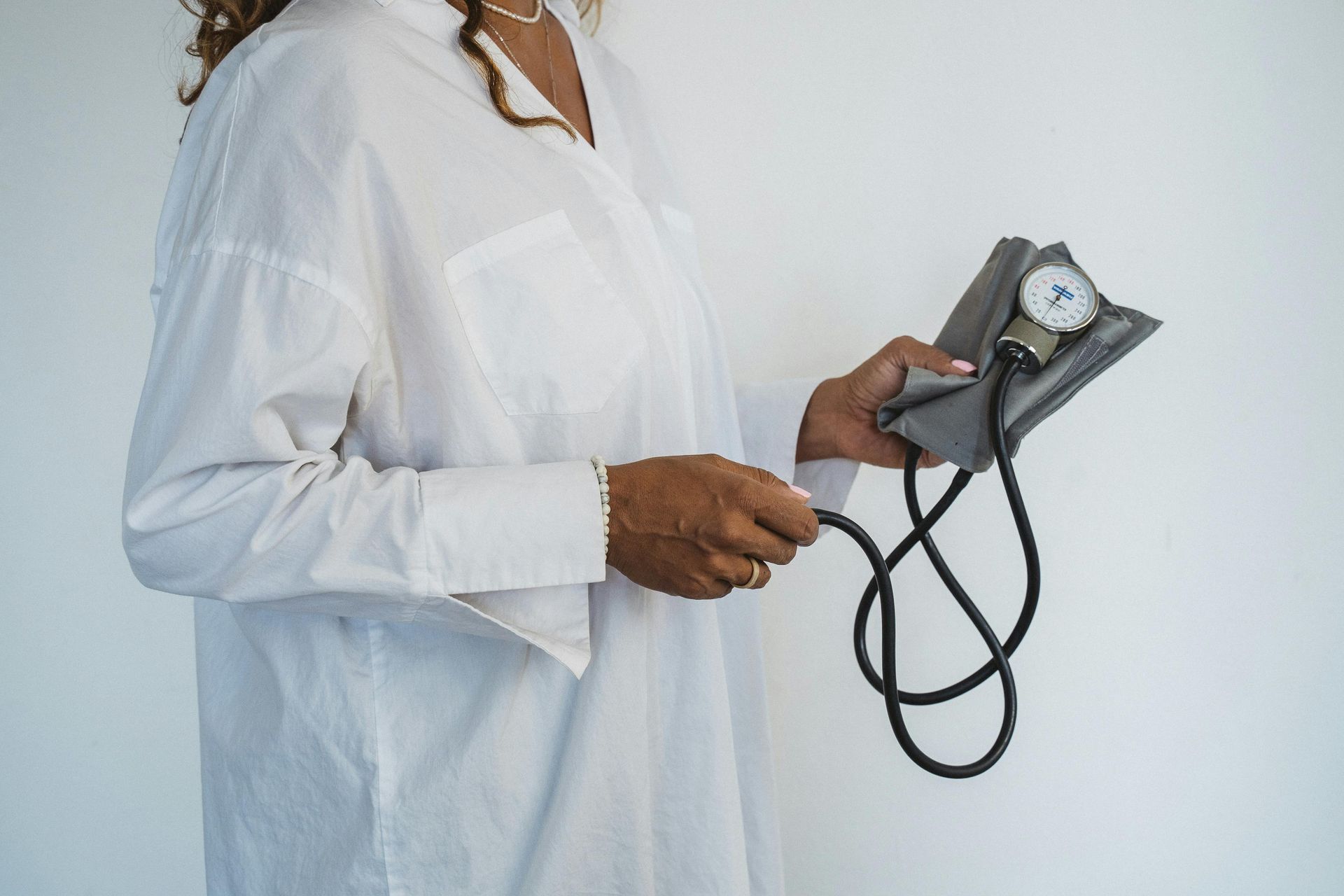 Person in white lab coat holding a blood pressure cuff against a white background