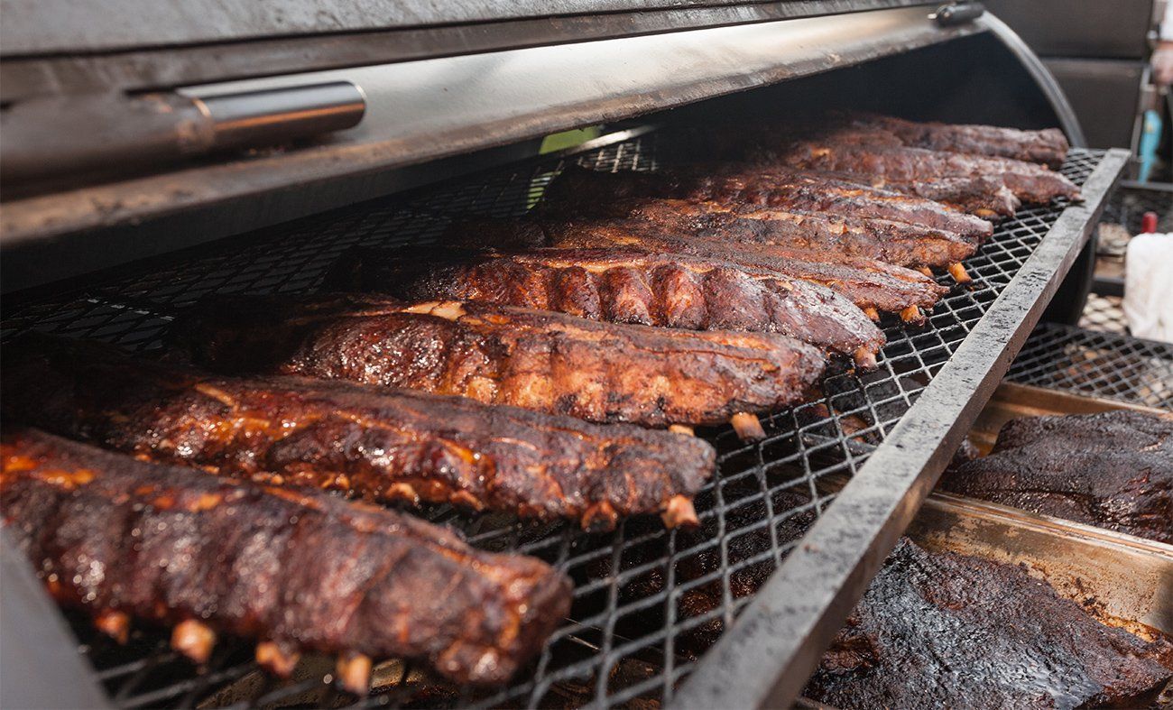 A bunch of ribs are cooking on a grill.