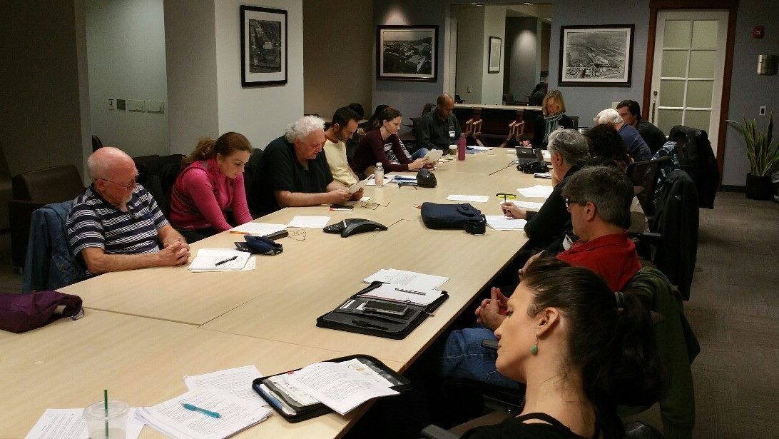 A group of people are sitting at a long table in a conference room.