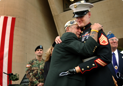 A man in a military uniform is hugging another man