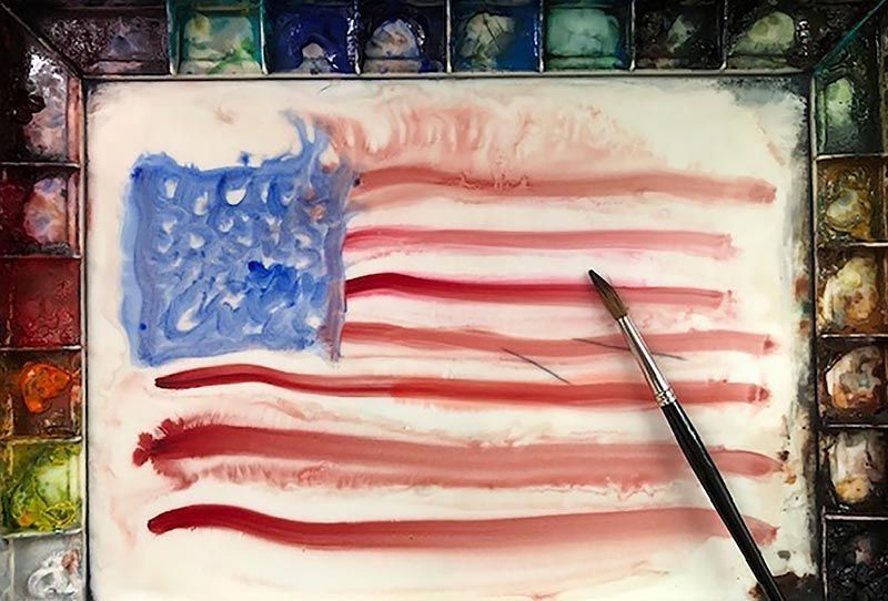 An american flag is being painted on a piece of paper with a brush.