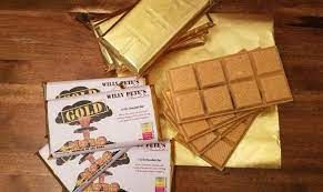 A pile of gold bars and chocolate bars on a wooden table.