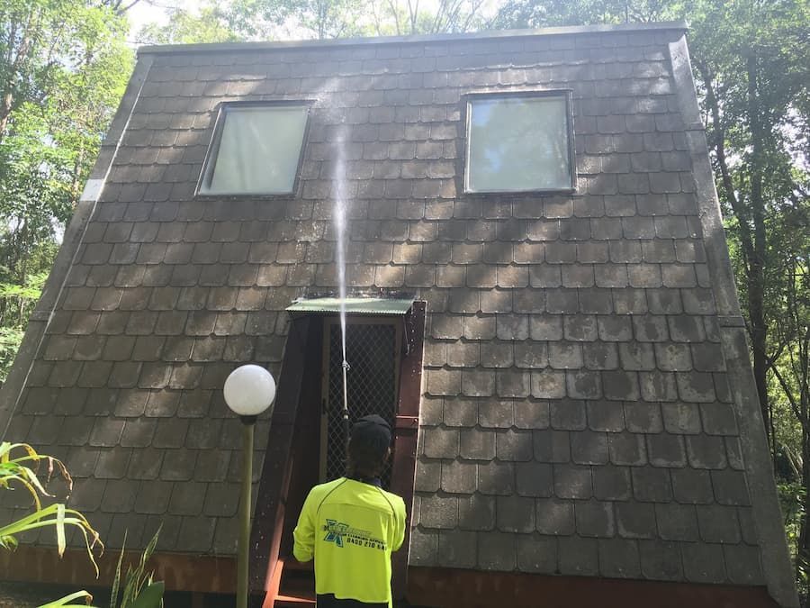 Man Spraying a Concrete House With a Pressure Washer — Excess Cleaning in Mudgeeraba, QLD