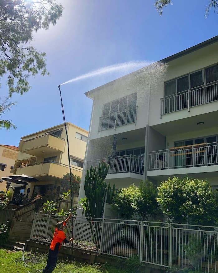 Cleaning the Outside of the Building Using a Long Spray — Excess Cleaning in Robina, QLD