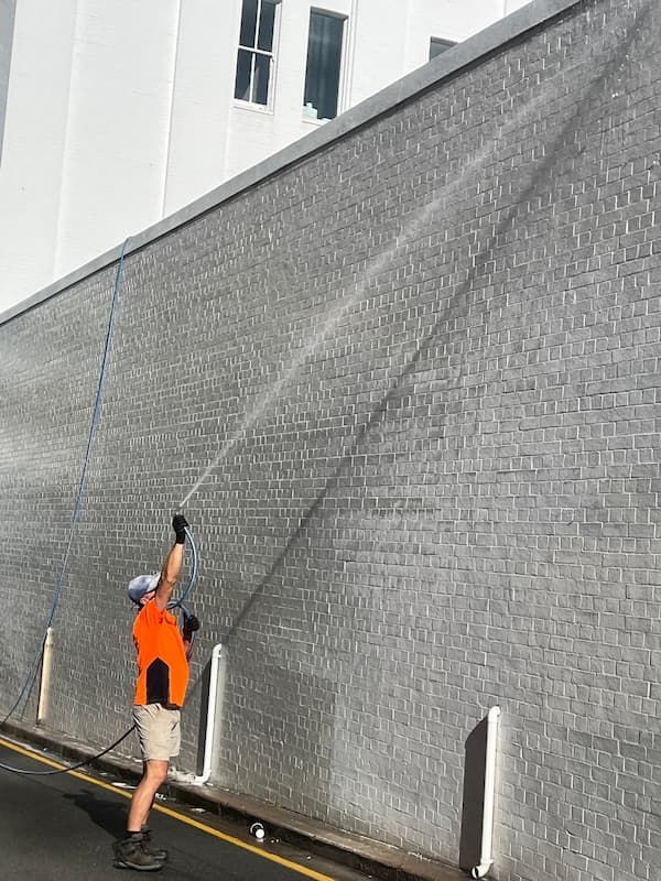 Man Spraying a Wall With a Hose — Excess Cleaning in Molendinar, QLD