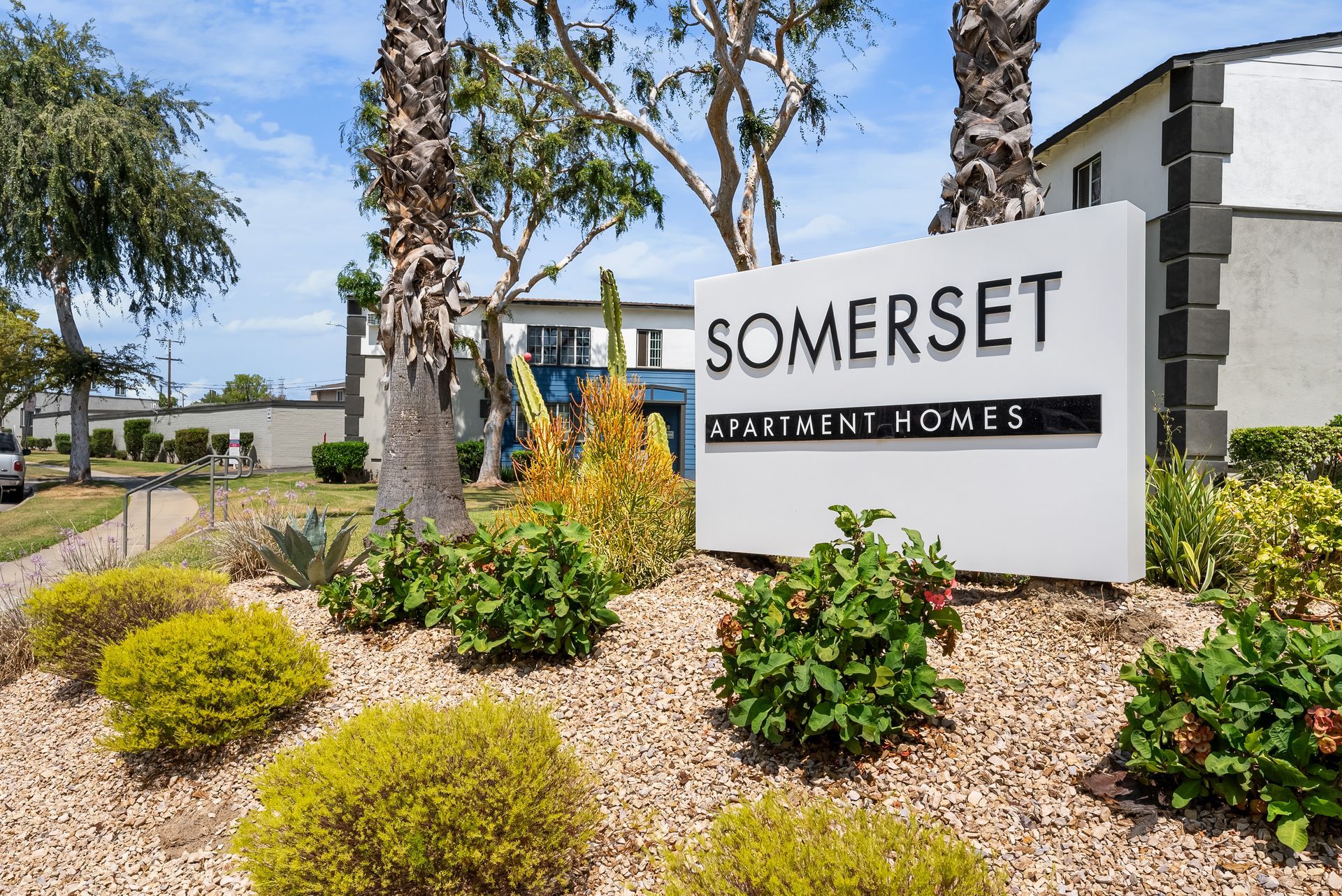 Sign for Somerset Apartment Homes with landscaping, under a blue sky.