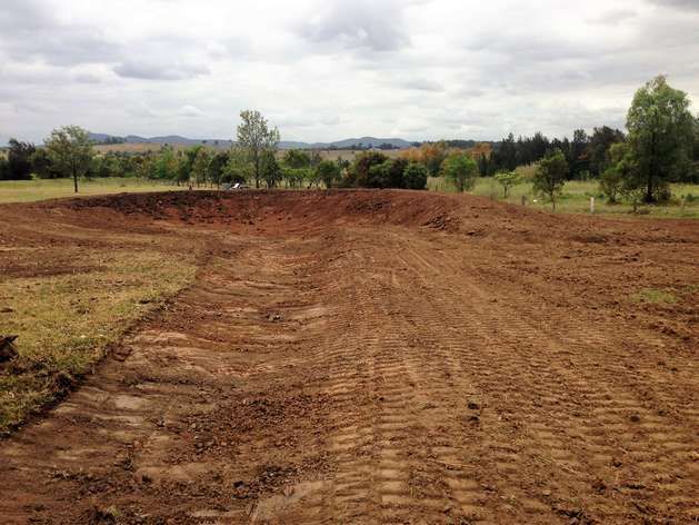 A Dirt Road is Going Through a Field With Trees in the Background — SMH Valley Fencing & Maintenance In Pokolbin, NSW