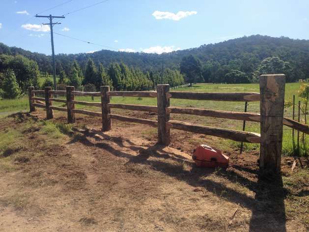 A Wooden Fence Surrounds a Field With Mountains in the Background — SMH Valley Fencing & Maintenance In Millfield, NSW