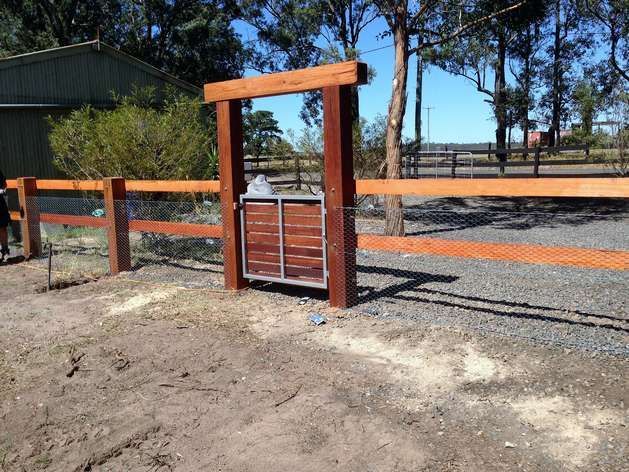 A Wooden Fence With a Gate in the Middle of a Dirt Field — SMH Valley Fencing & Maintenance In Millfield, NSW