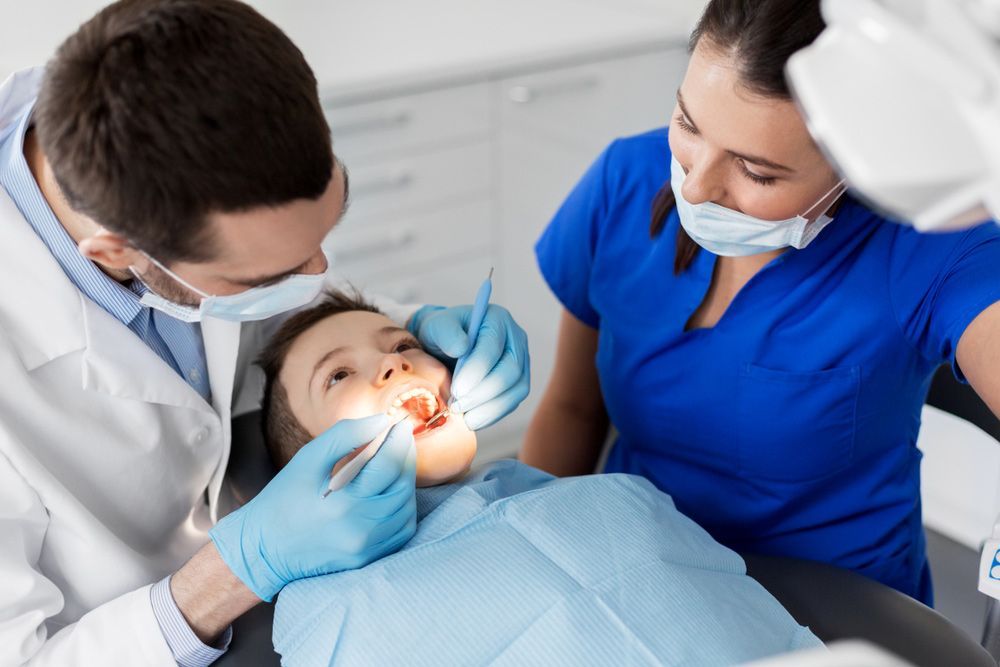 A Child Is Getting His Teeth Examined By A Dentist And A Nurse — Regal's Dental In Emu Park, QLD