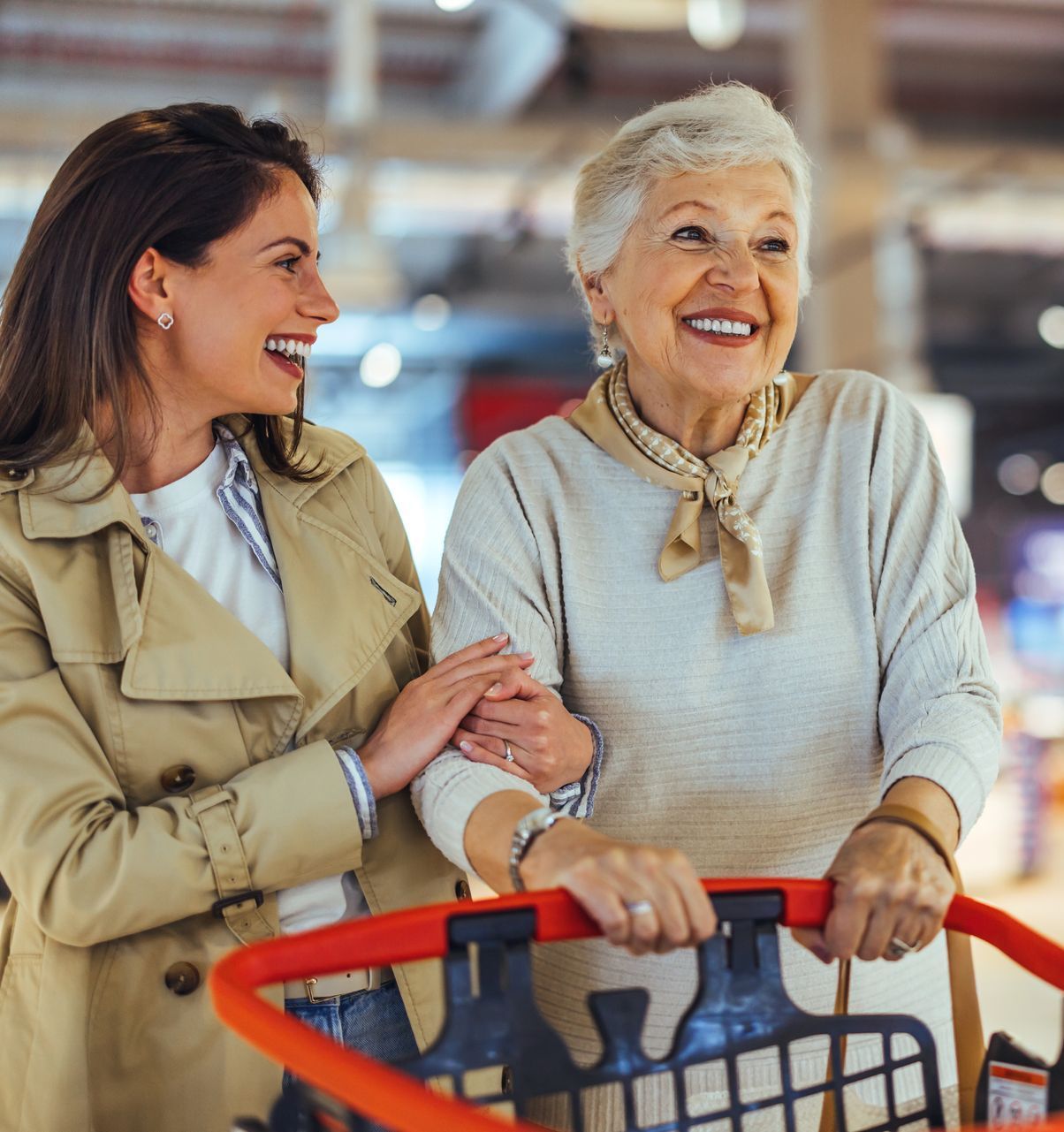Due donne sono in piedi una accanto all'altra e una sta spingendo un carrello della spesa