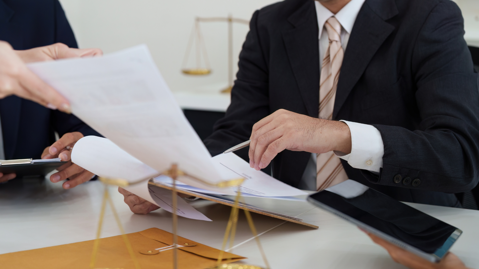 Lawyers reviewing documents at a desk, scales of justice in background.