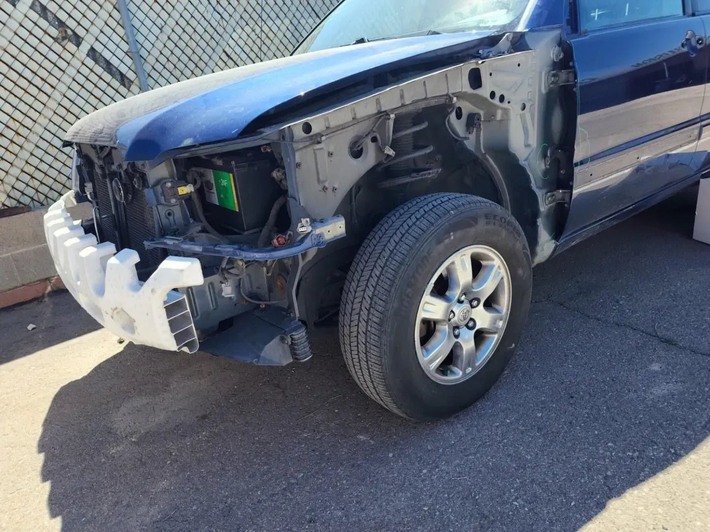 A blue truck with its hood removed is parked on the side of the road.