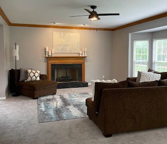A living room with a couch , chair , ottoman and fireplace.