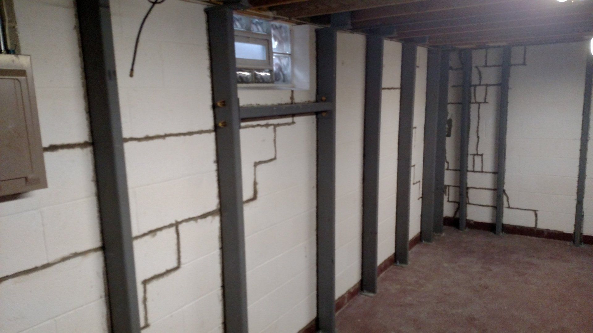 basement waterproofing paint A basement with cracks in the walls and a window.