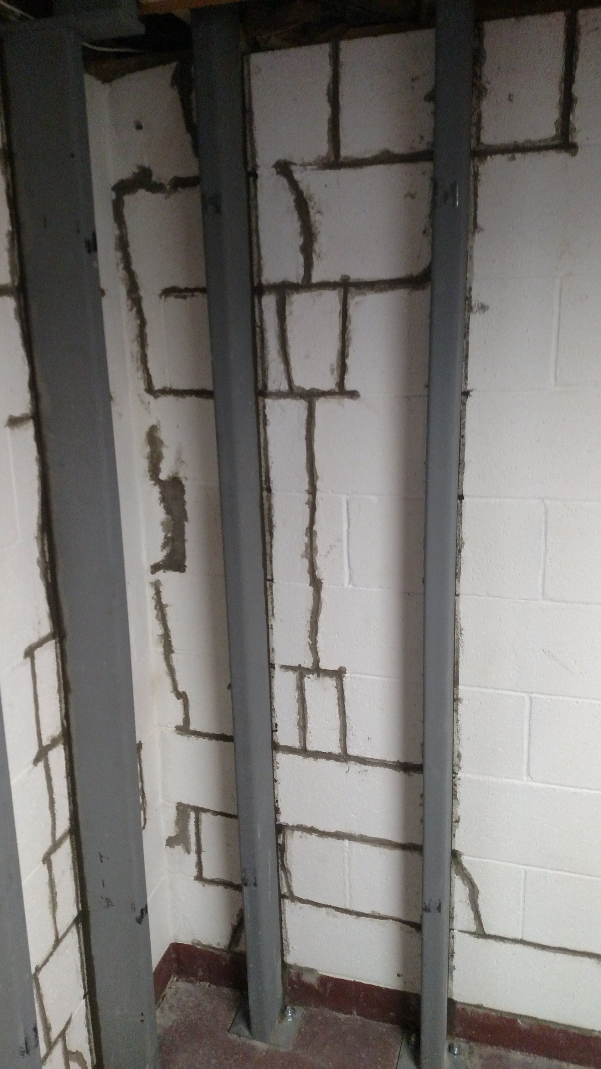basement wall crack repair A room with a brick wall and a metal frame.