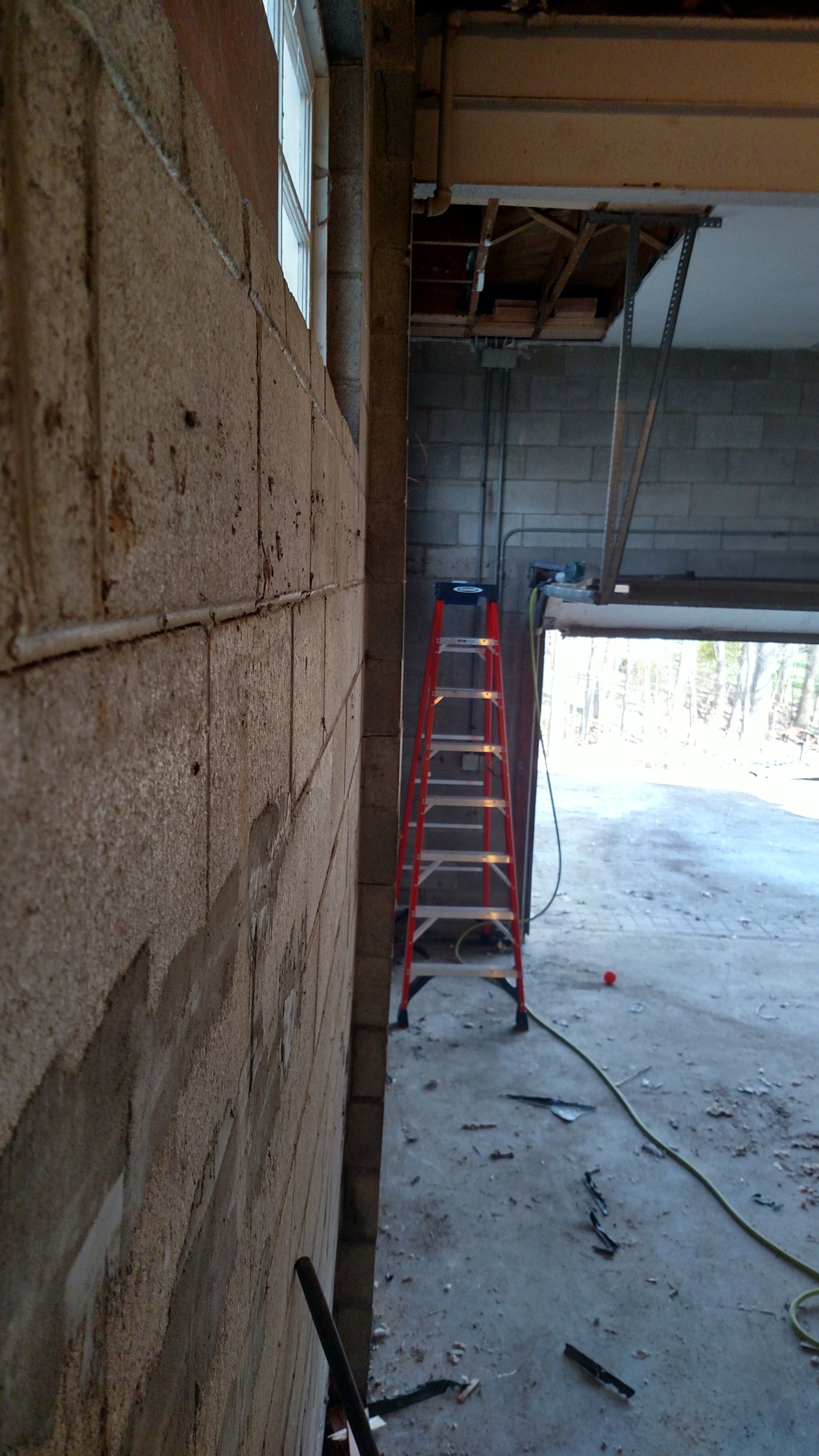 concrete block foundation A red ladder is sitting in a garage next to a brick wall.