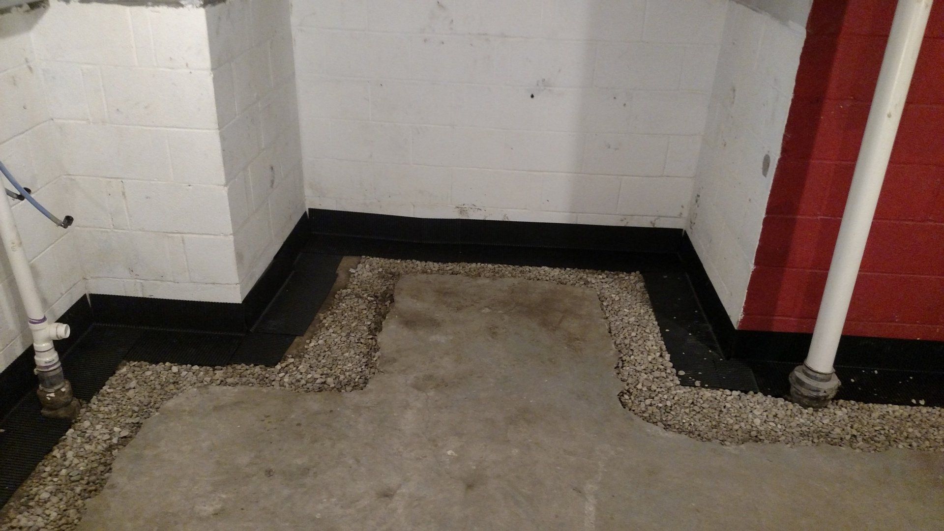 leaking basement wall A corner of a room with a black border and gravel on the floor.