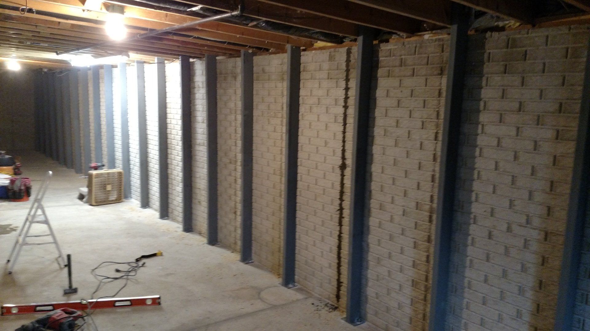 wall bracing A basement with brick walls and metal beams.