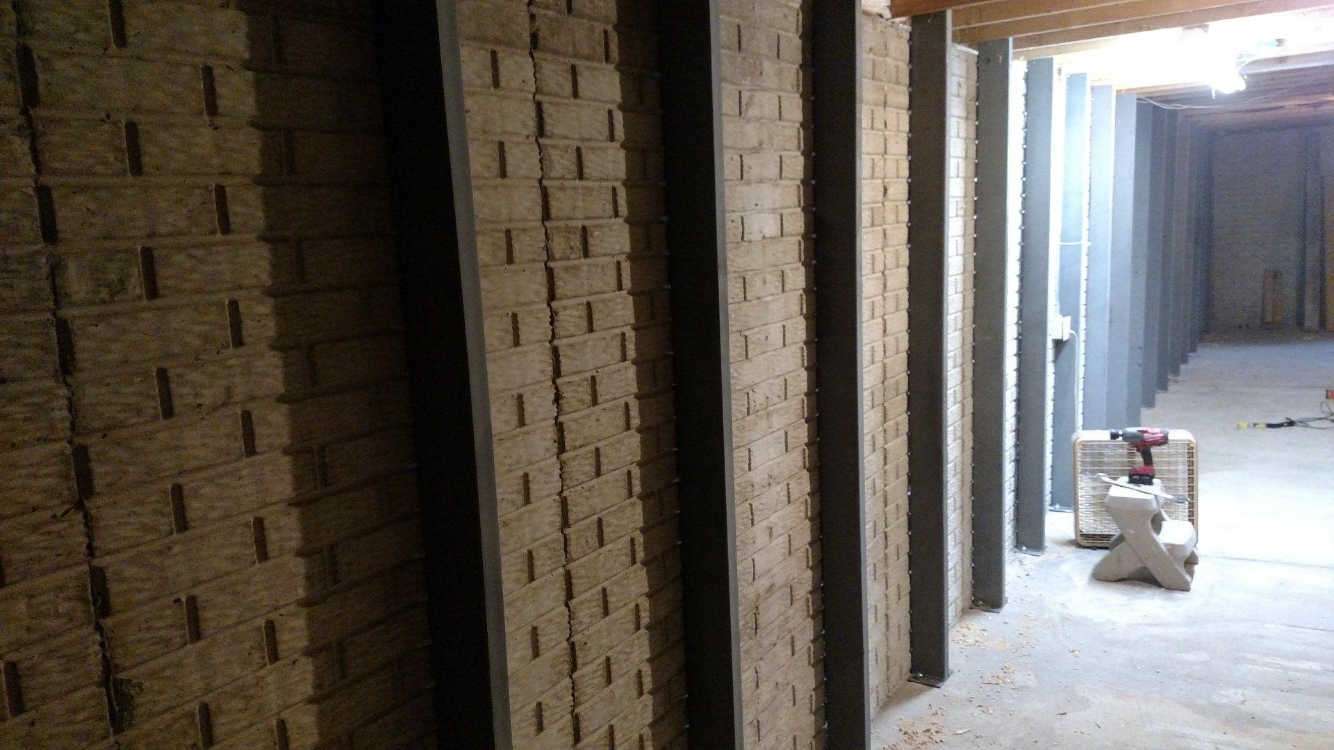 best foundation repair near me A long hallway with brick walls and a drill on the floor.