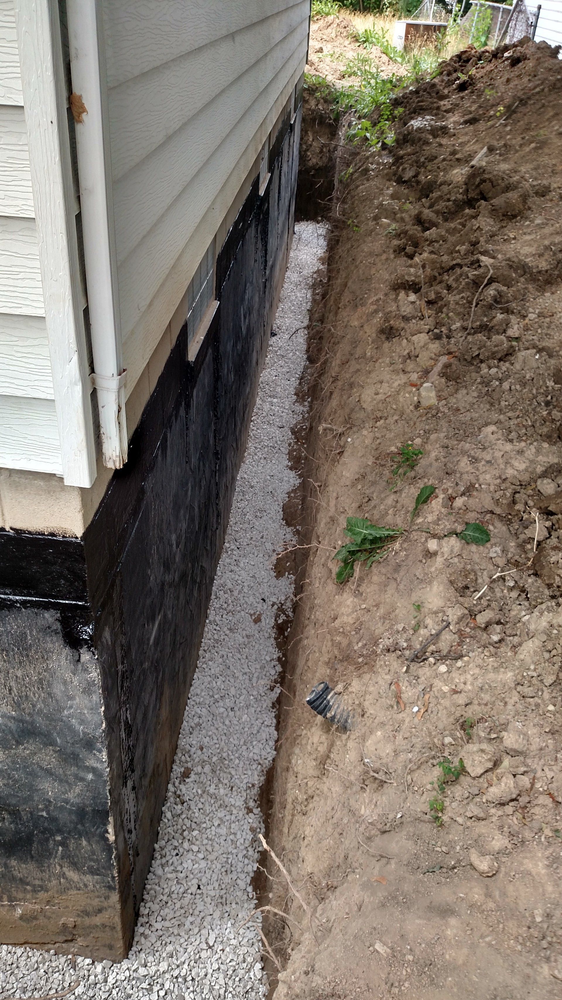 foundation leak A house with a drainage system being installed on the side of it.