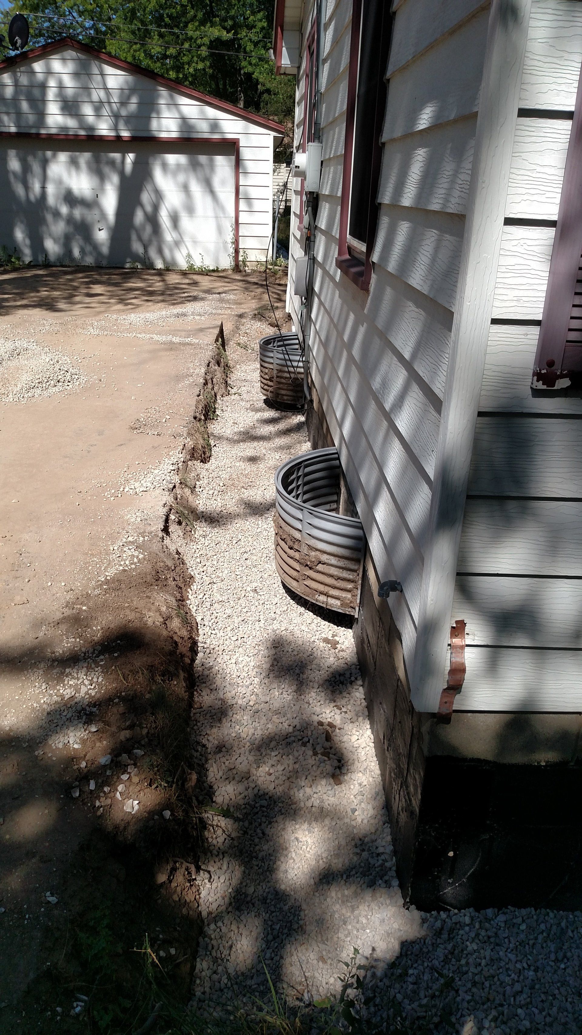 exterior foundation waterproofing A white house with a lot of dirt on the side of it.