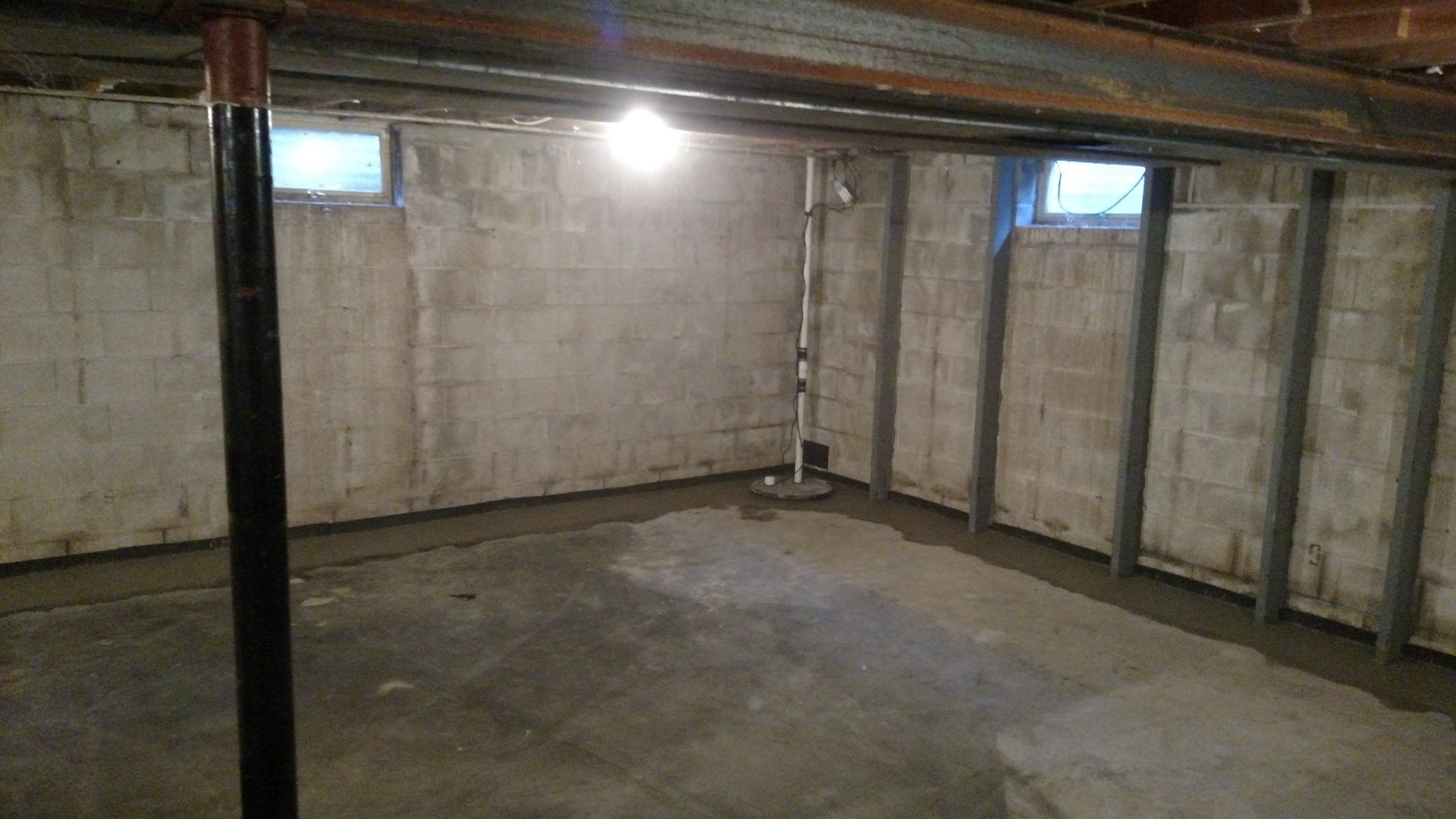 sump pump alarm An empty basement with concrete walls and a light on the ceiling.