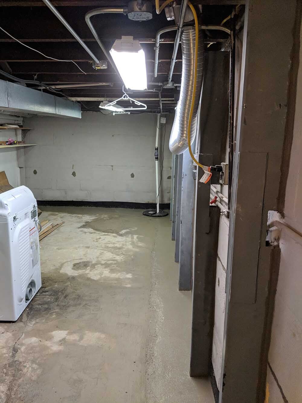 basement floor crack A dirty basement with a washer and dryer in it.