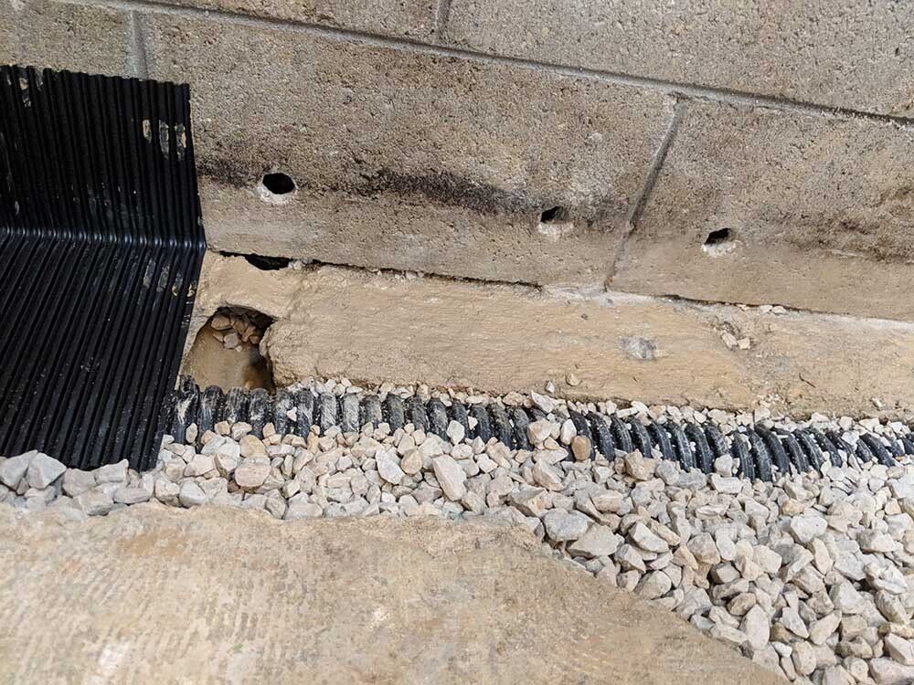 foundation cracking A pile of gravel is sitting next to a brick wall.