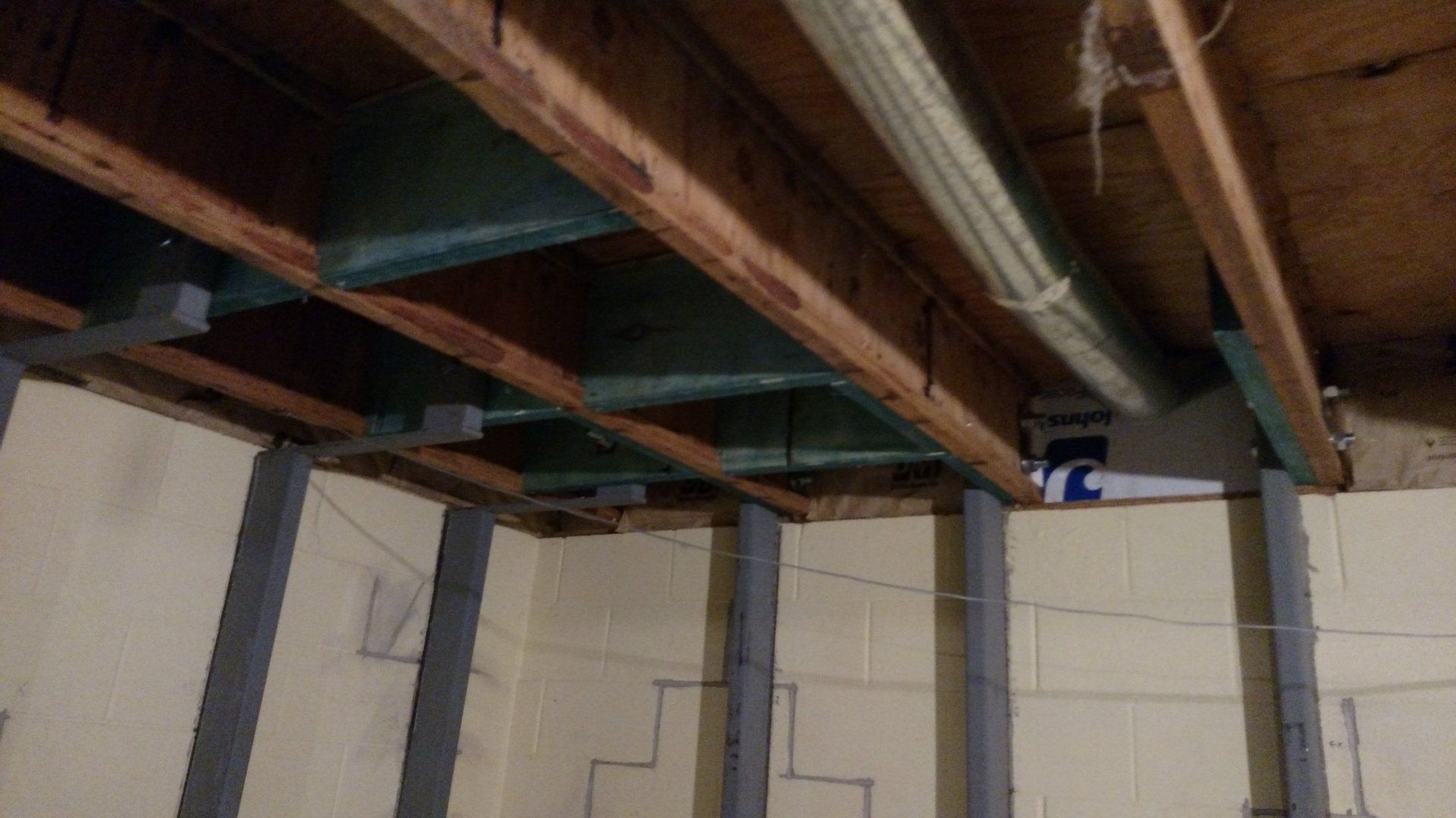 foundation contractor The ceiling of a basement with wooden beams and pipes.