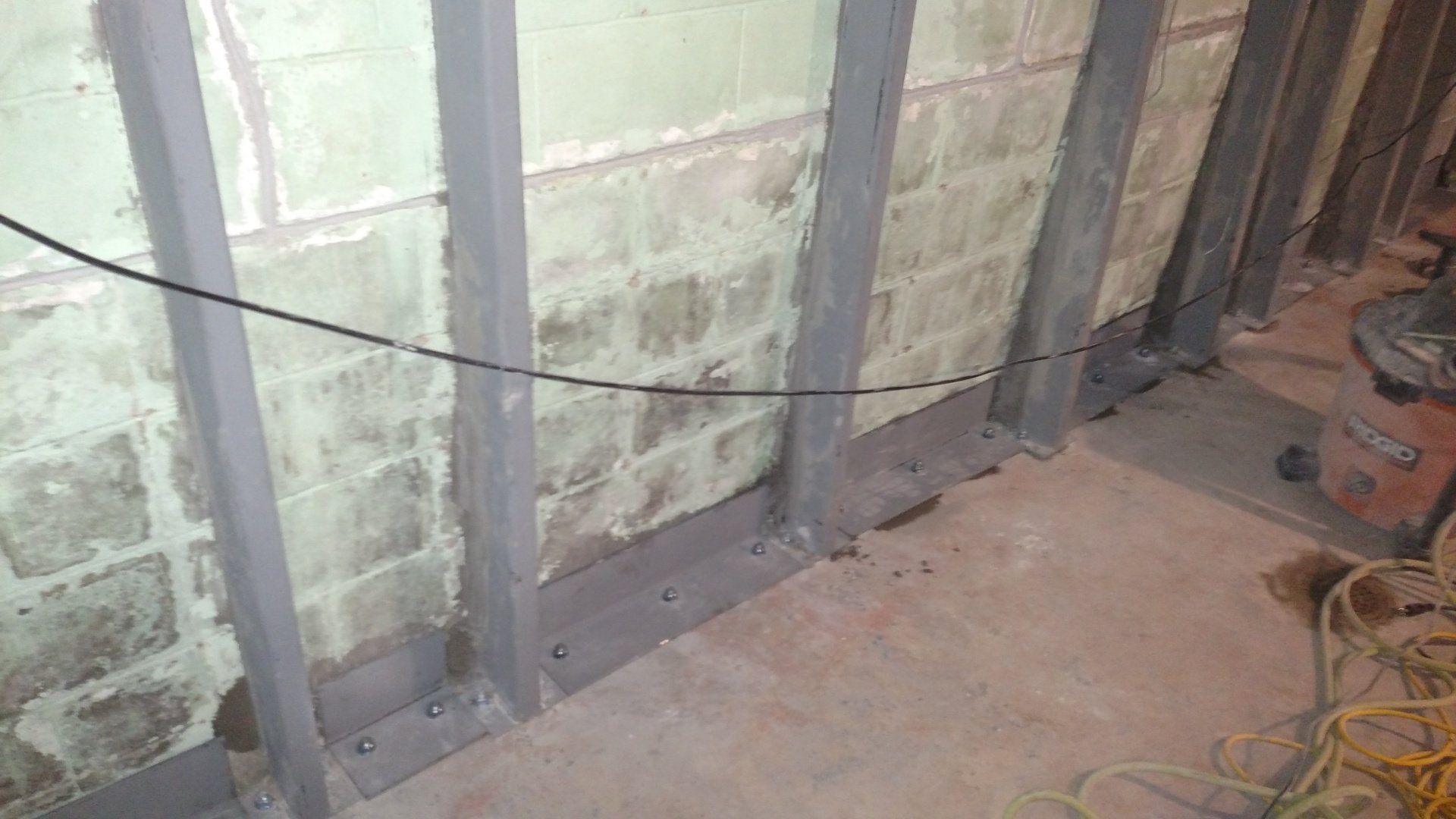 foundation blocks A brick wall with a metal frame around it is being remodeled in a basement.