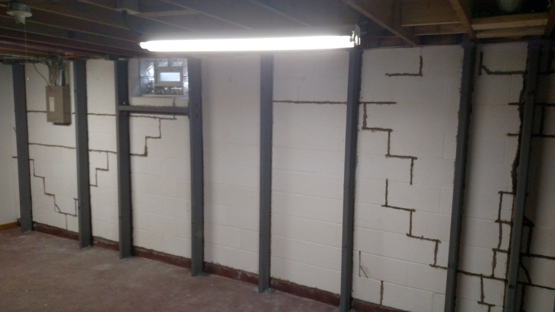 foundation cracks A basement with stairs and a light on the ceiling.