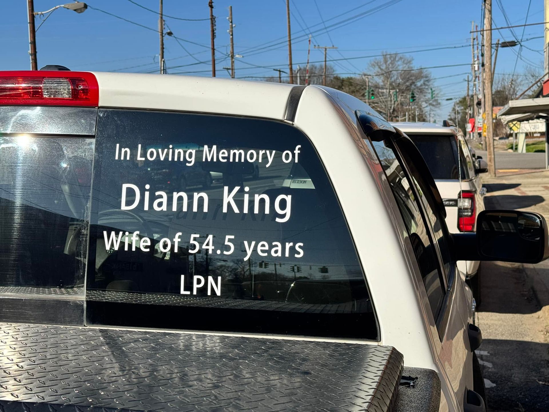 A truck with a sticker on the back window that says in loving memory of diann king wife of 54.5 years lpn