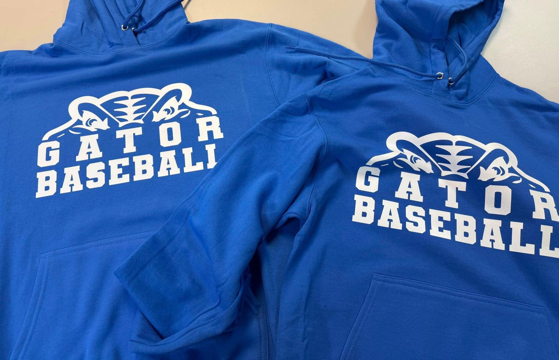 Two blue gator baseball hoodies are on a table