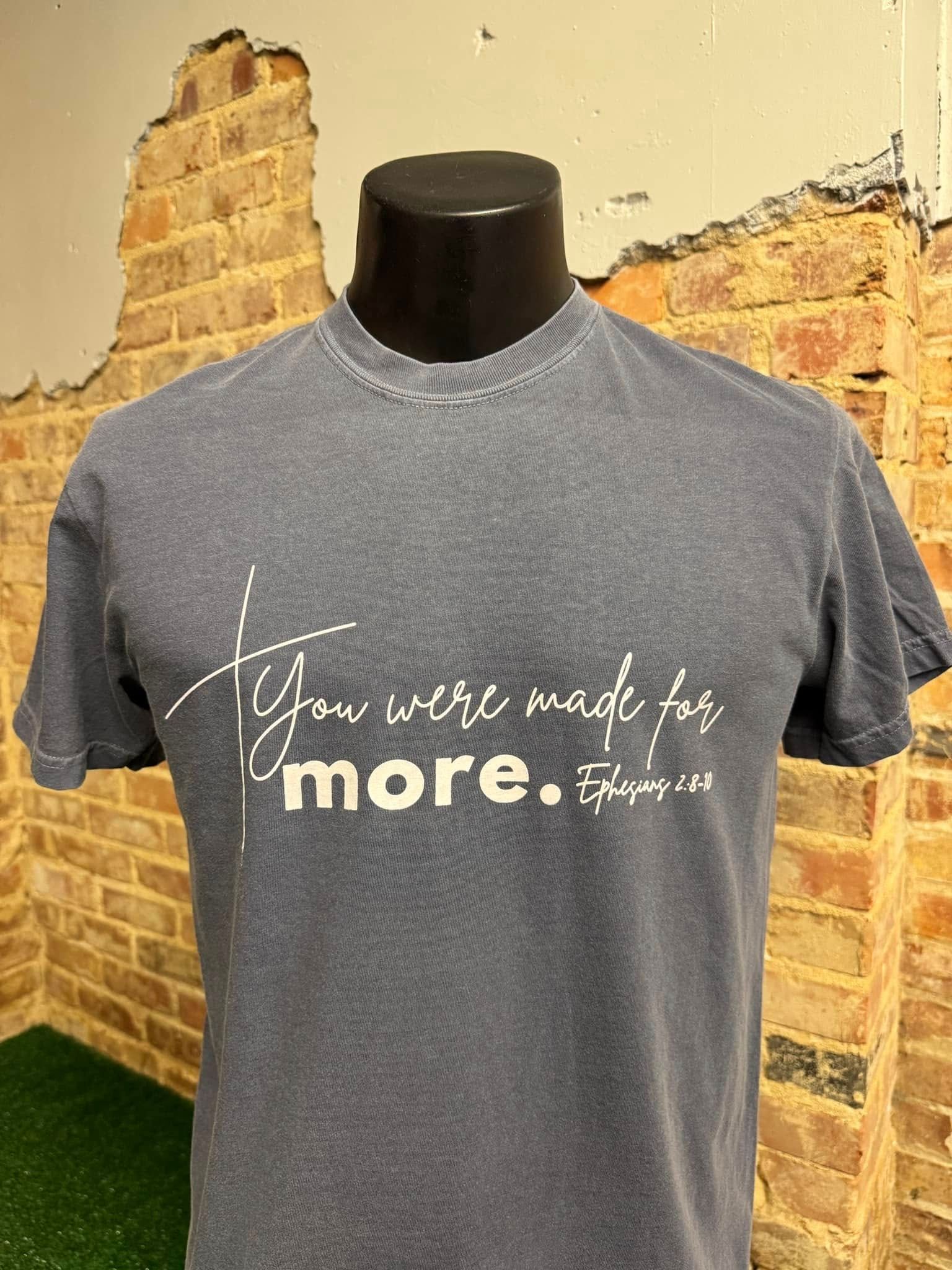 A t-shirt that says `` you were made for more '' is on a mannequin in front of a brick wall.