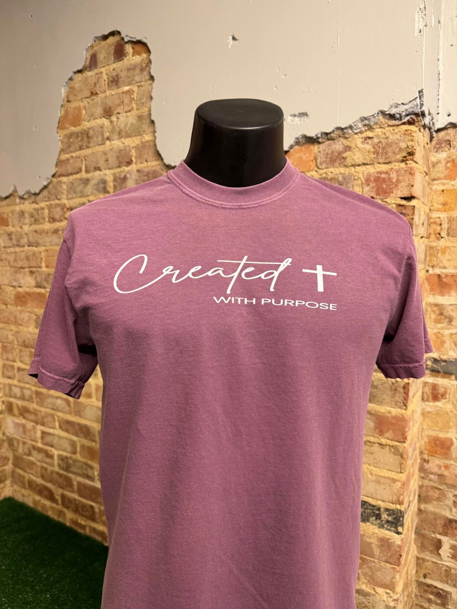 A purple t-shirt is on a mannequin in front of a brick wall.
