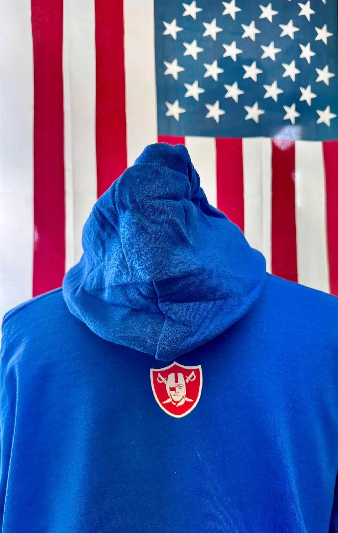 The back of a blue hoodie is shown in front of an american flag